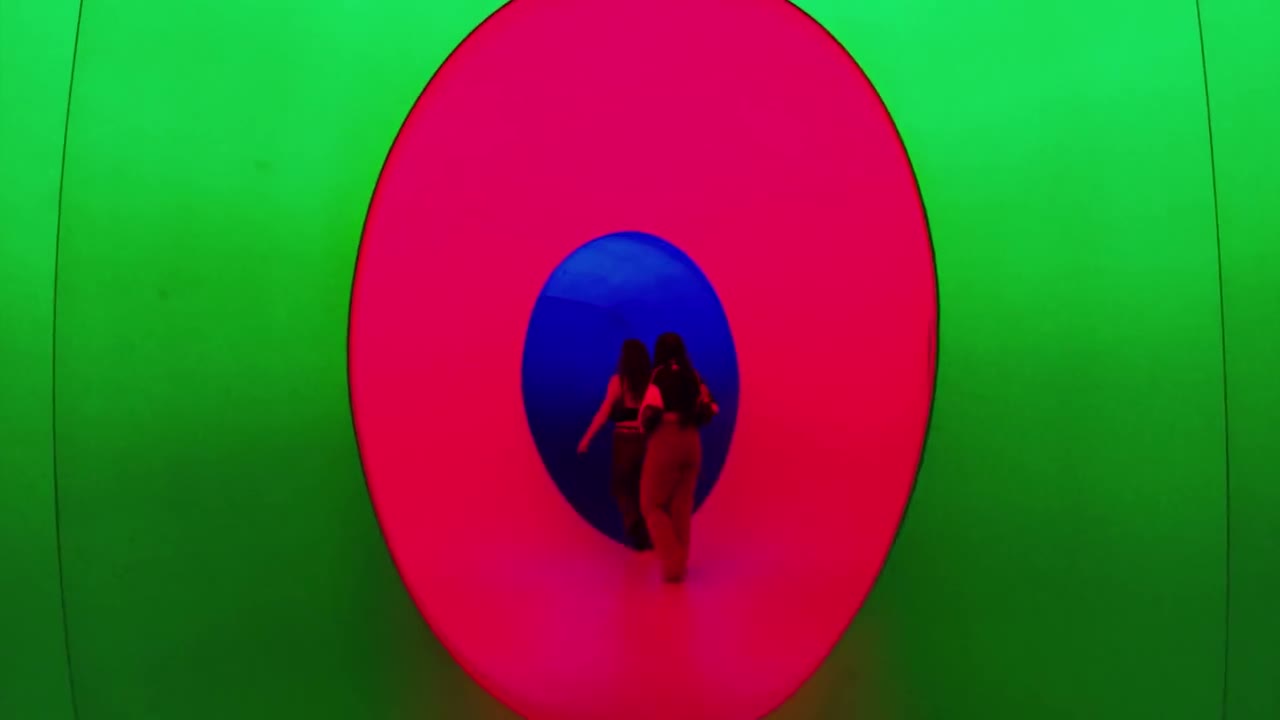 People walking into a colourful oval light tunnel