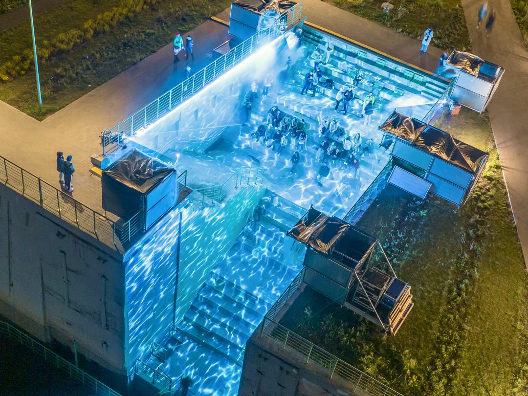 Concrete basin flooded with blue water-light projections at night
