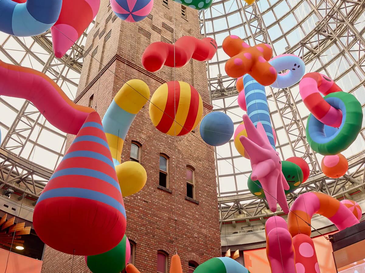 Colourful inflatable sculptures floating in a glass atrium