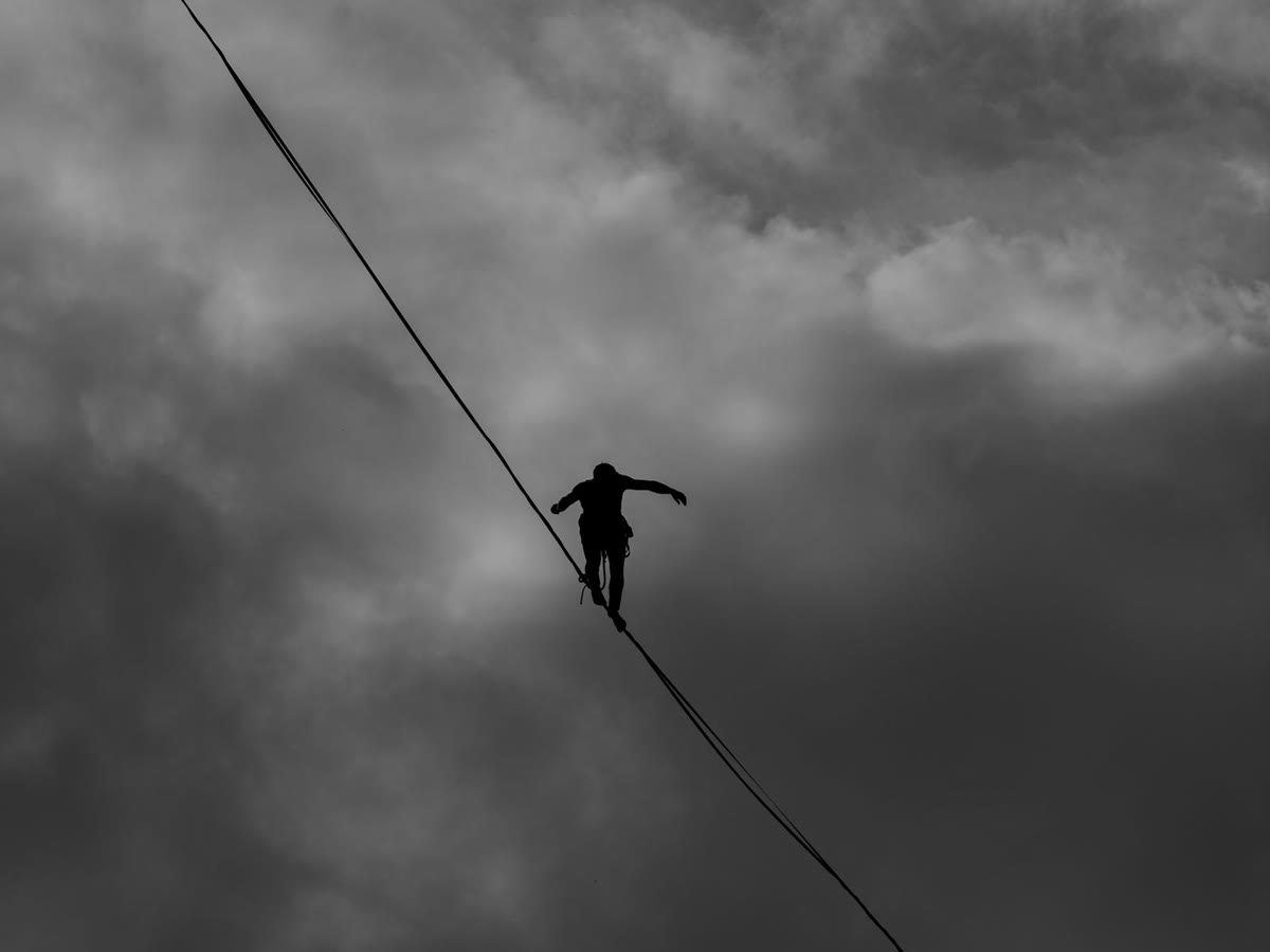 Tightrope walker silhouetted against a dramatic sky